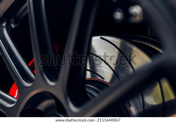 Slotted brake rotor with shadow from wheel spoke\
with red brake caliper