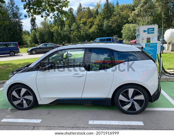 Šenčur, Slovenia - 29. August 2021: \
BMW i3 electric car on a green parking place for charging during a\
problem-free trip from Innsbruck Austria to\
Dubrovnik