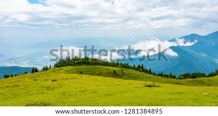 Slovenia mountains near the Kamnik city on Velika Planina pasture land. View of mountains with white clouds and blue sky, mist in the hill. Beautiful and tranquil nature, fresh grass.