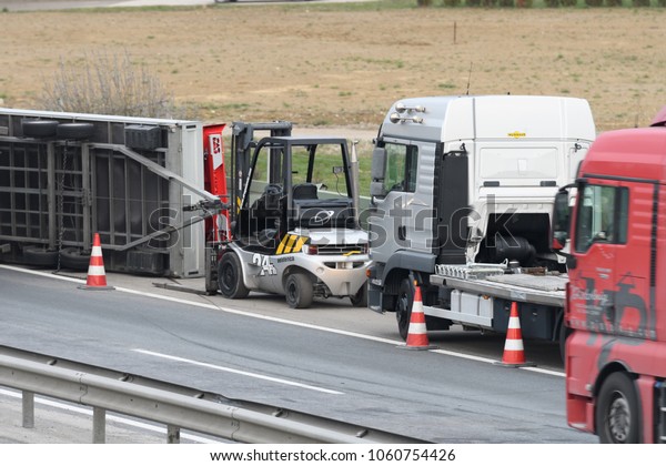 Slovenska\
Bistrica - March 23, 2018: Tow truck workers cleaning wreckage\
after traffic accident on highway after a small truck lost control\
and its trailer crashed into the security\
fence
