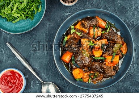 Slow braised beef chunks with roasted sweet potatoes in rich savory sauce, served in a bowl. Flat lay