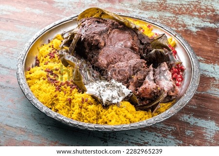 Slow cooked Omani lamb shuwa coated in rub of spices and wrapped in banana leaves served with rice and yoghurt as close-up on a rustic oriental tray