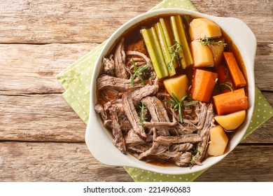 Slow Cooked Pot Roast With Carrots, Celery, Potatoes, Garlic And Gravy Closeup In The Bowl On The Wooden Table. Horizontal Top View From Above
