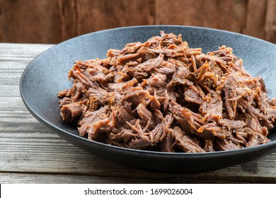 Slow Cooked Pulled Beef For Sandwiches In Black Ceramic Bowl