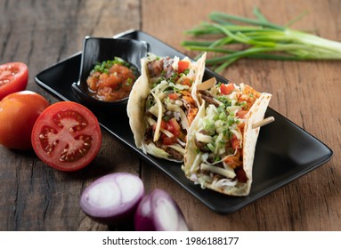 Slow Cooked Short Ribs On Tortillas With A Spring Onion Tomato Salsa Isolated On Wooden Table