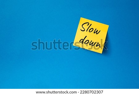 Slow down symbol. Orange steaky note with words Slow down. Beautiful blue background. Business and Slow down concept. Copy space.