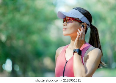 Slow Motion Of Asian Confident Woman Wearing True Earbuds Look Far Away With Smile And She Is Ready To Run In Forest Training For Triathlon