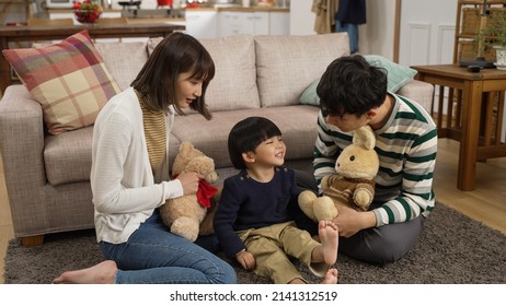 Slow Motion Of Asian Dad, Mom And Baby Son Playing With Toy Animals On Living Room Floor At Home. The Man Uses Stuffed Bunny’s Hand To Touch Cute Son’s Face