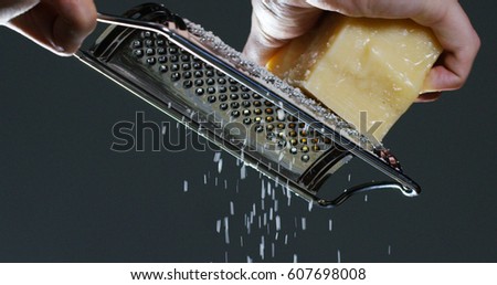 Slow motion of A cook grater Parmesan cheese, typical Italian cheese, on the plate just freshly brewed. Concept: Italian cuisine, cheese, restaurant and food.