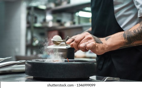 Slow Motion. Cropped Image Of Restaurant Chef Hands With Several Tattoos Adding A Spice To Fresh Cooked Pasta Carbonara.