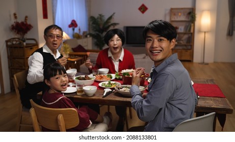 Slow Motion Of Happy Family At Dinner Table Turning Head And Look At Camera In Surprise As Someone Is Serving The Main Dish For Reunion Meal At Home