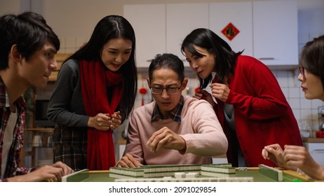 slow motion happy father drawing tile in beckoning other mahjong players formoney while his wife and daughter celebrating for his win with clenched fist. word translation: luck