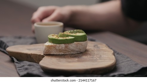 Slow Motion Man Eating Breakfast With Caibatta With Avocado And Cream Cheese And Cup Of Espresso