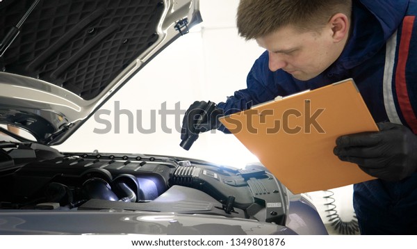 Slow Motion
Man (Male) professional in working form and flashlight with a
folder in his hands checks a car engine for serviceability. Concept
of: Autocentre, Service,
Diagnostics.