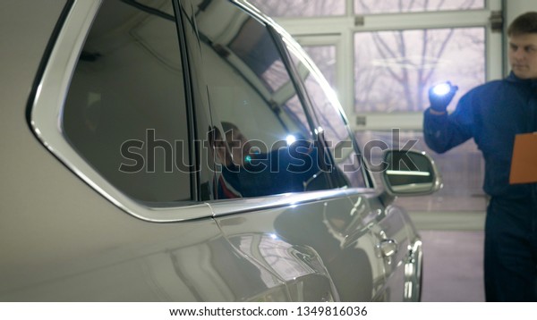 Slow Motion Man (Male) professional in\
working uniform and flashlight folder in his hands checks the car\
from all sides for serviceability Concept of: Car center, Service,\
Diagnostics.