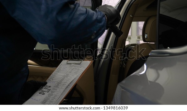 Slow Motion Man (Male) professional in\
working uniform and flashlight folder in his hands checks the car\
from all sides for serviceability Concept of: Car center, Service,\
Diagnostics.