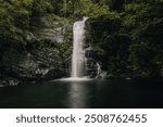 slow motion Maya King Waterfall in the Silver Creek Camp, Southern Belize jungle near the Southern Highway with dark water and rocks