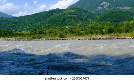 Slow Motion Of Stormy Mountain River. Beautiful Mountain Scenery In The Background. 