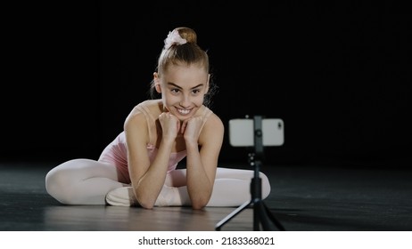 Slow Motion Teen Girl Ballerina Child Teenager Gymnast Dancer Sitting On Floor In Dance Class Watching In Mobile Phone Camera On Tripod Online Video Call Conference Chat With Remote Teacher Trainer