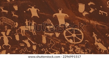 Slow pan and tilt to showcase the numerous individual petroglyphs and demonstrate the vast age differences, 500 year-old panels inscribed over 2000 to 4000 year-old symbols at Newspaper Rock in Utah.