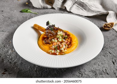 Slow roast leg of lamb with pumpkin puree and vegetables salsa. Roasted lamb with vegetables on gray stone table. Composition with meat dish on stone background. Meat menu ideas - Powered by Shutterstock