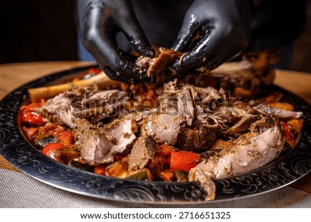 Slow roasted lamb hand pulled by chef over baked vegetables on a large platter showcasing halal friendly festive cuisine and rich traditional restaurant flavors