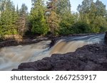 Slow shutter shot of a section of Temperance River with shore rocks in the foreground