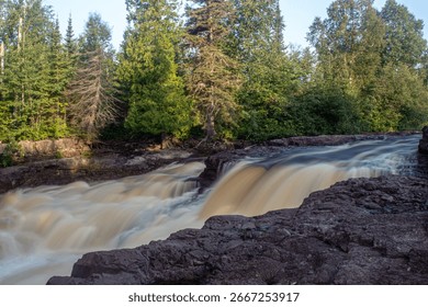 Slow shutter shot of a section of Temperance River with shore rocks in the foreground