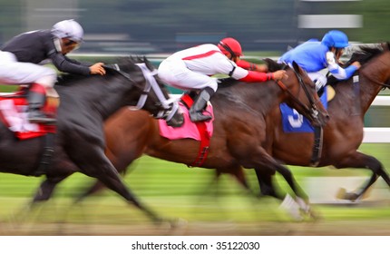 Slow Shutter Speed Rendering Of Three Jockeys Racing Their Horses For The Win In A Thoroughbred Horse Race.