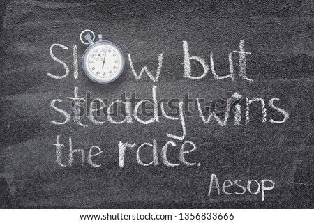 Slow but steady wins the race - quote of ancient Greek story teller Aesop written on chalkboard with stopwatch instead of O