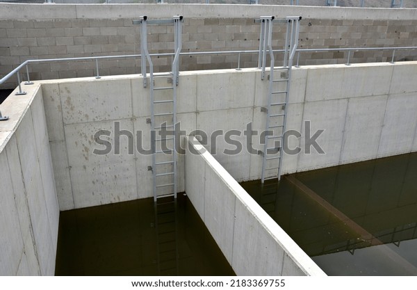 sludge, retention sump, concrete tank divided by a\
partition. two control galvanized metal ladders lead into the\
water. rainwater is purified and sedimented here. sewage and\
drainage water treatment\
