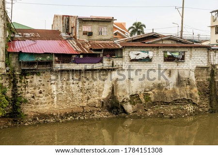 A slum or squatter area along a heavily polluted river bordering Metro Manila and Cavite. Disregard of zoning laws near riverbanks. A polluted river.