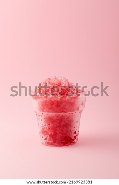 Slushie or Slush - drink on pink\
background. Fruit shaved ice in disposable plastic cup. Take away\
food. Refreshing summer drink. Vertical orientation, copy\
space.