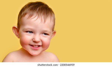 Sly toddler baby, studio yellow background, copy space. Portrait of an insidious child with red cheeks. Kid age one year and two months