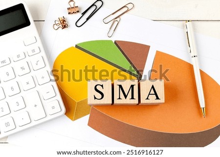  SMA -Simple Moving Average concept with wooden blocks, pie chart, calculator, and office supplies on white desk.