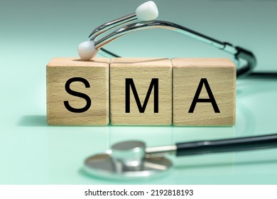 SMA, spinal muscular atrophy, Written on wooden blocks, a rare disease in which, due to a genetic defect, neurons in the spinal cord responsible for muscle contraction and relaxation gradually die. - Shutterstock ID 2192818193