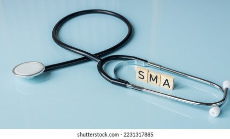 SMA, spinal muscular atrophy, Written on wooden blocks, a rare disease in which, due to a genetic defect, neurons in the spinal cord responsible for muscle contraction and relaxation gradually die - Shutterstock ID 2231317885