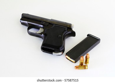 Small .25 Caliber Automatic Handgun On Neutral Background With Clip And Bullets.