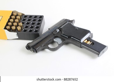 Small .25 Caliber Hand Gun And Open Box Of Cartridges To Indicate A Weapon Being Loaded.