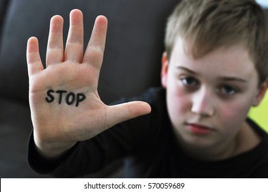 Small abused boy holding his hand with the word 'STOP' written on it. Concept of domestic violence and child abusement.