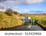Small adjustable weir in a stream with a mirror smooth reflecting water surface in a polder in the Netherlands. It