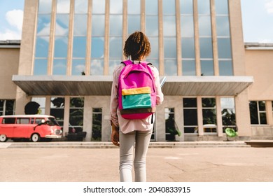 Small African-American kid schoolchild pupil student going to school, standing at the school yard before classes lessons. New academic year semester. Welcome back to school! - Powered by Shutterstock