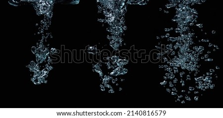 Small air bubbles float to the surface of the water. Bubbles of water on a black background. water splashes