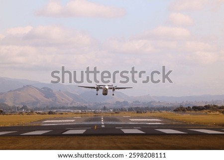 Small aircraft taking off from a scenic runway with mountains in the background. Perfect for travel ads, aviation industry, logistics, adventure tourism, and editorial use in news and business.