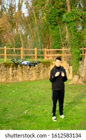 Small Aircraft Without Crew. Teenage Boy Bokeh Piloting A Drone With His Smartphone In A Park Outside.