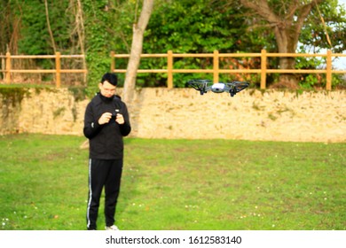 Small Aircraft Without Crew. Teenage Boy Bokeh Piloting A Drone With His Smartphone In A Park Outside.