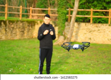 Small Aircraft Without Crew. Teenage Boy Bokeh Piloting A Drone With His Smartphone In A Park Outside.