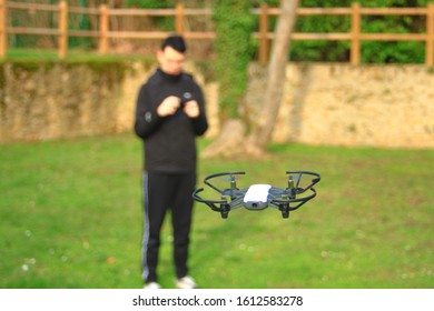 Small Aircraft Without Crew. Teenage Boy Bokeh Piloting A Drone With His Smartphone In A Park Outside.