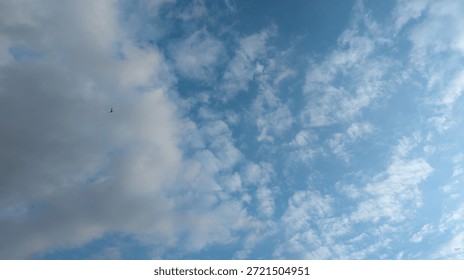 Small airplane flying through dramatic clouds in blue sky