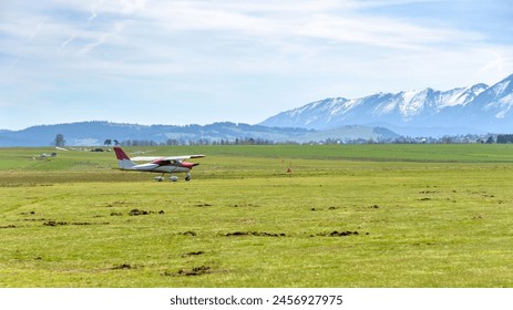 Small airplane on the sport grass airfield in Nowy Targ. Tatra mountain in the background. - Powered by Shutterstock